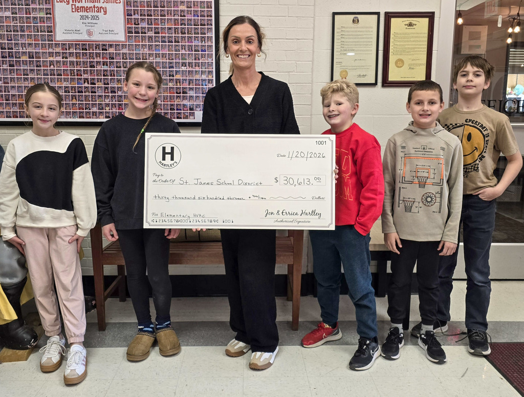 Students pose with Hartley's Climate Control representative who is holding a large check that shows the donation to the school. 