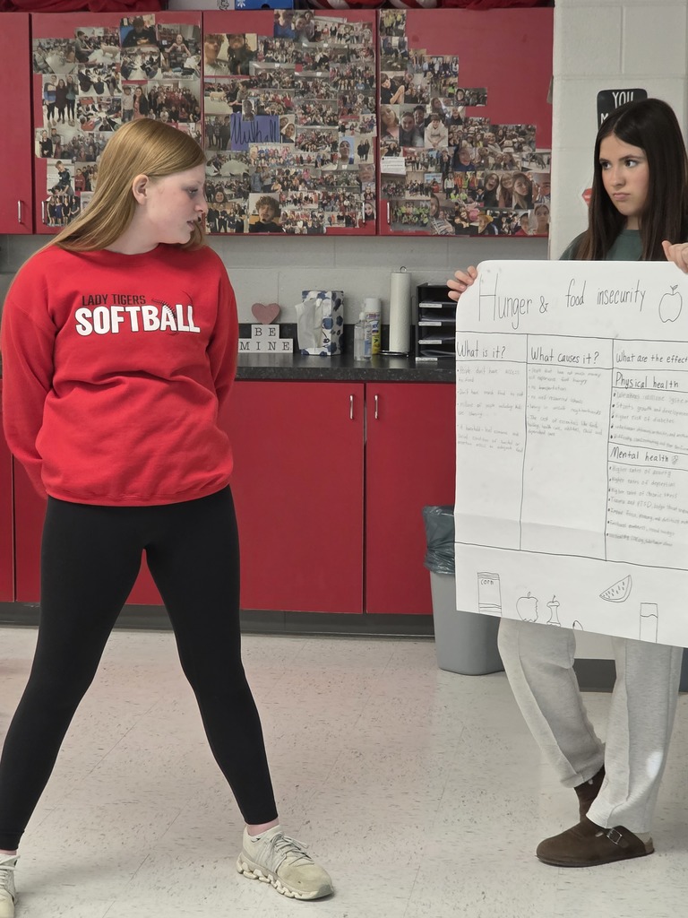 Agriculture students hold their presentation posters in front of the class.
