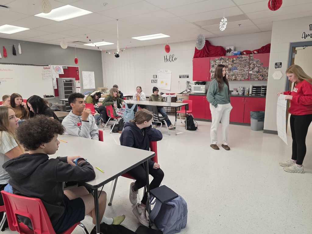 Agriculture students hold their presentation posters in front of the class.