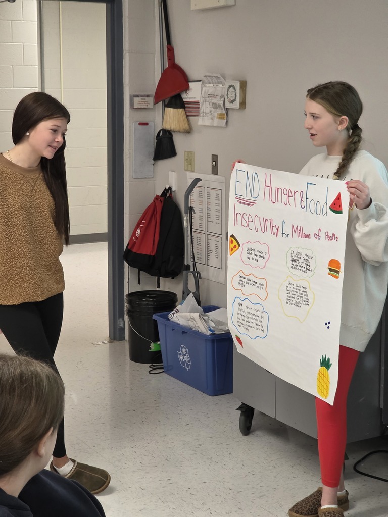 Agriculture students hold their presentation posters in front of the class.