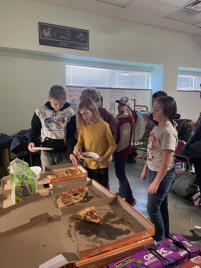 Band students grab pizza out of the box in their classroom. 