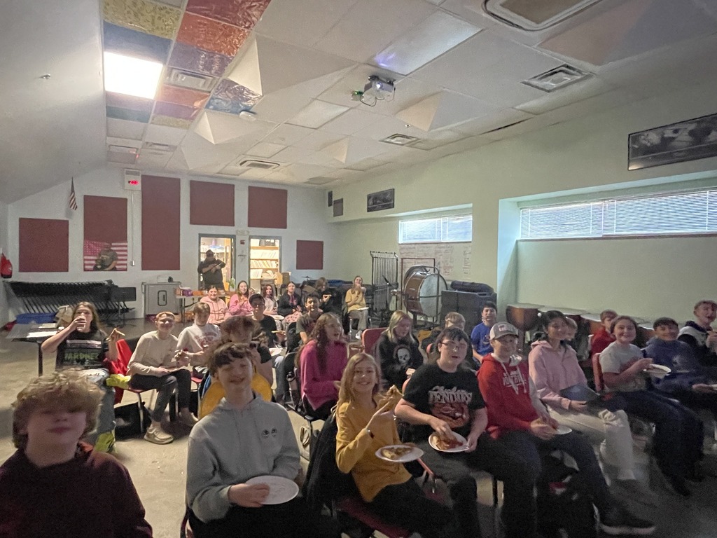 Band students grab pizza out of the box in their classroom. 