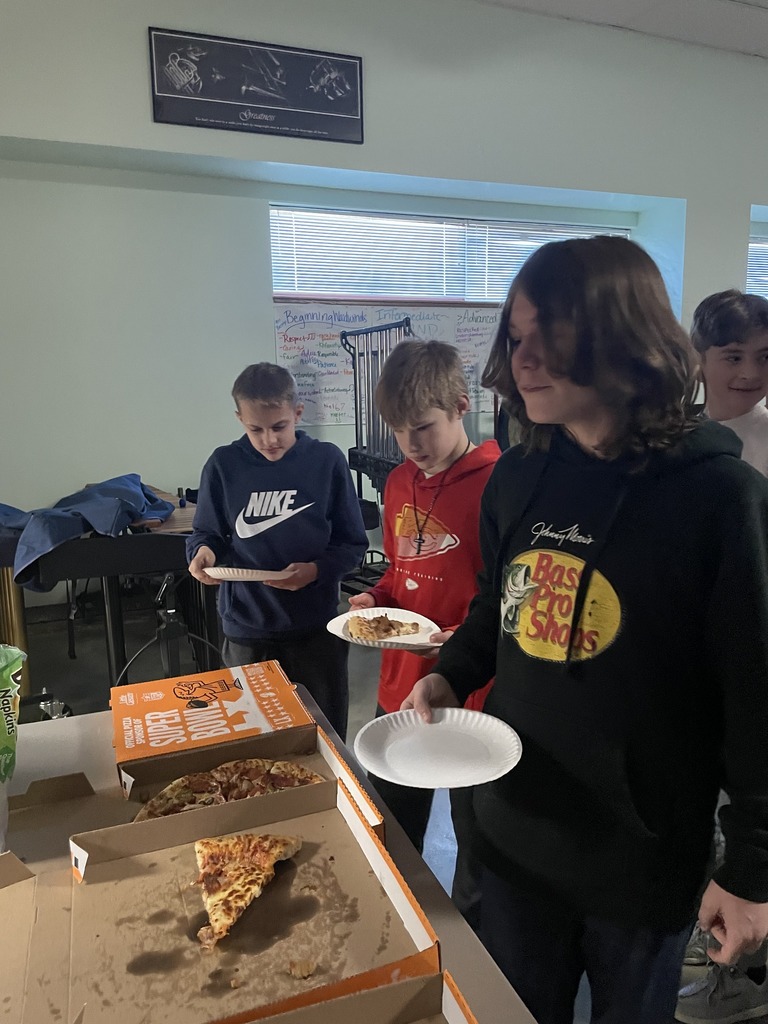 Band students grab pizza out of the box in their classroom. 