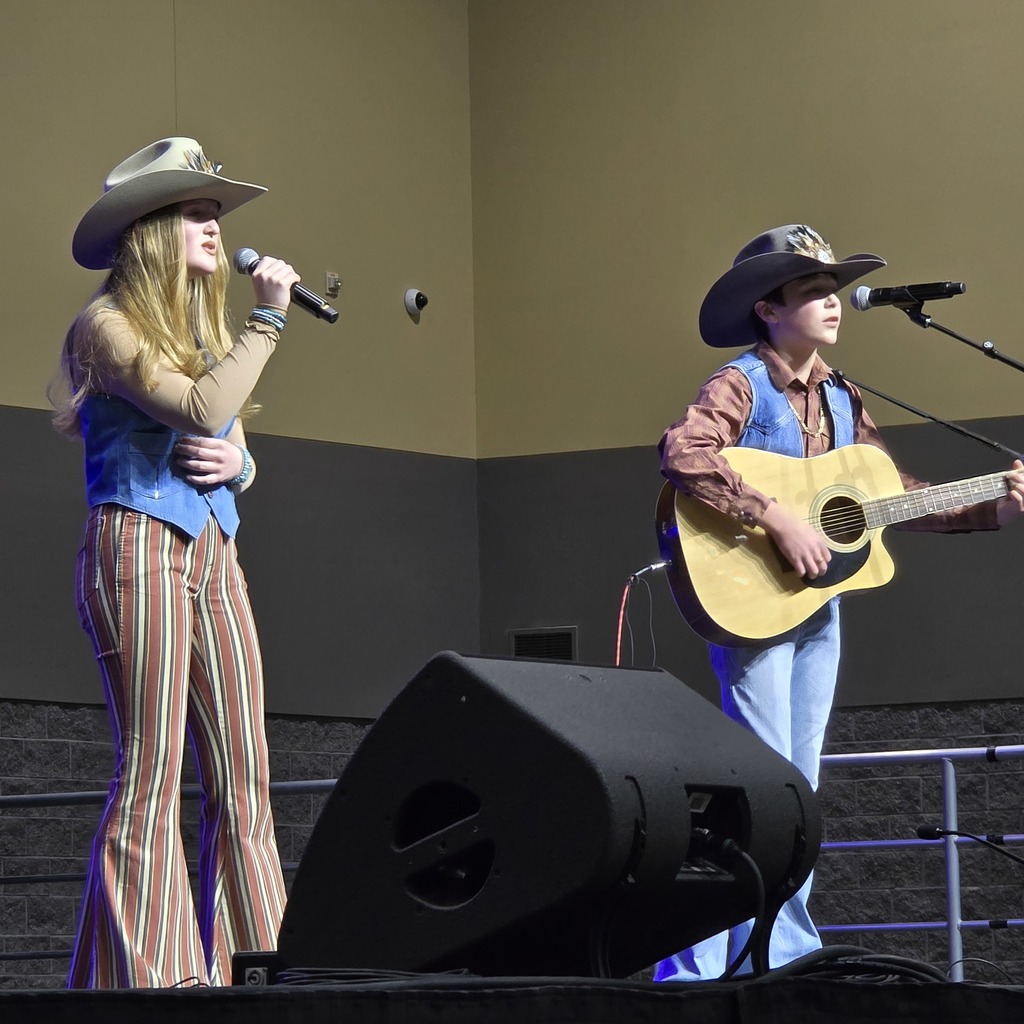 Two students stand on stage performing. 