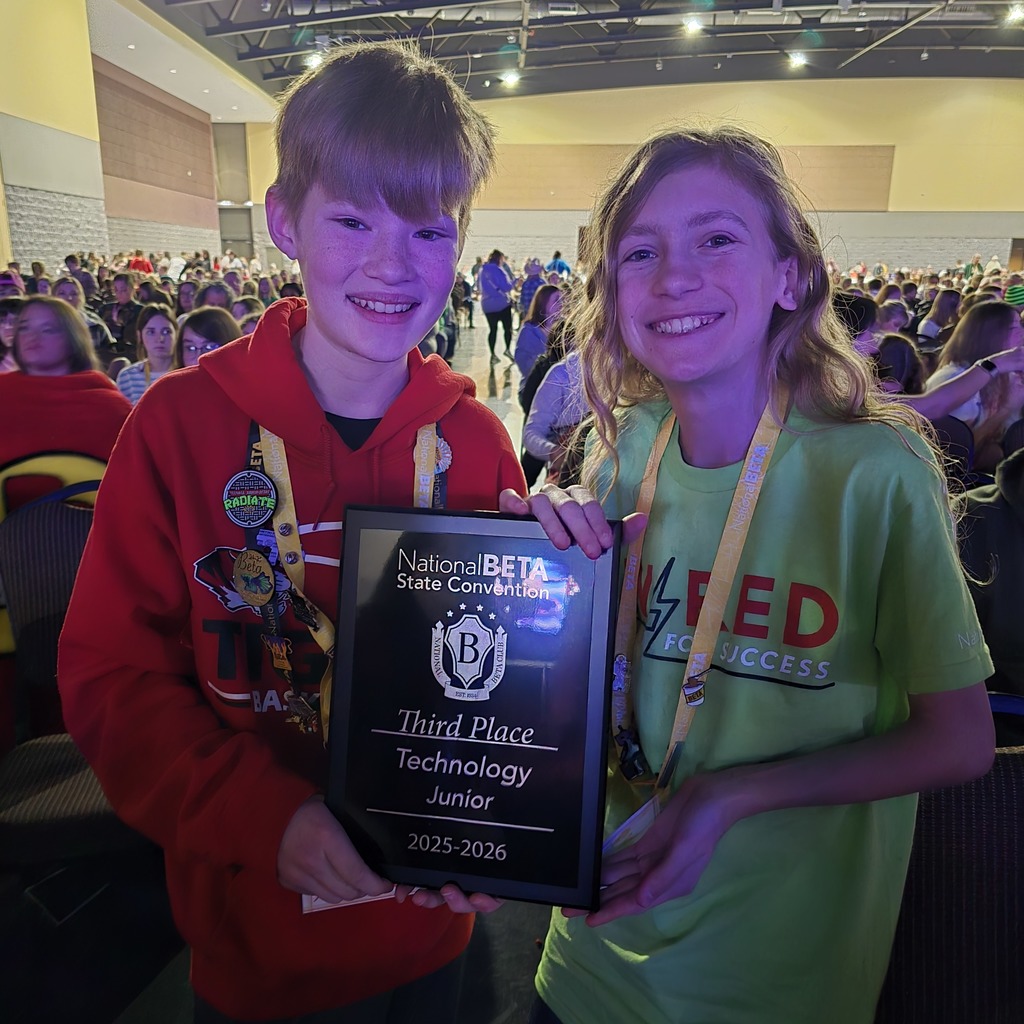 Two children in a large room pose with a plaque that reads "Third Place Junior Technology 2015-2016."