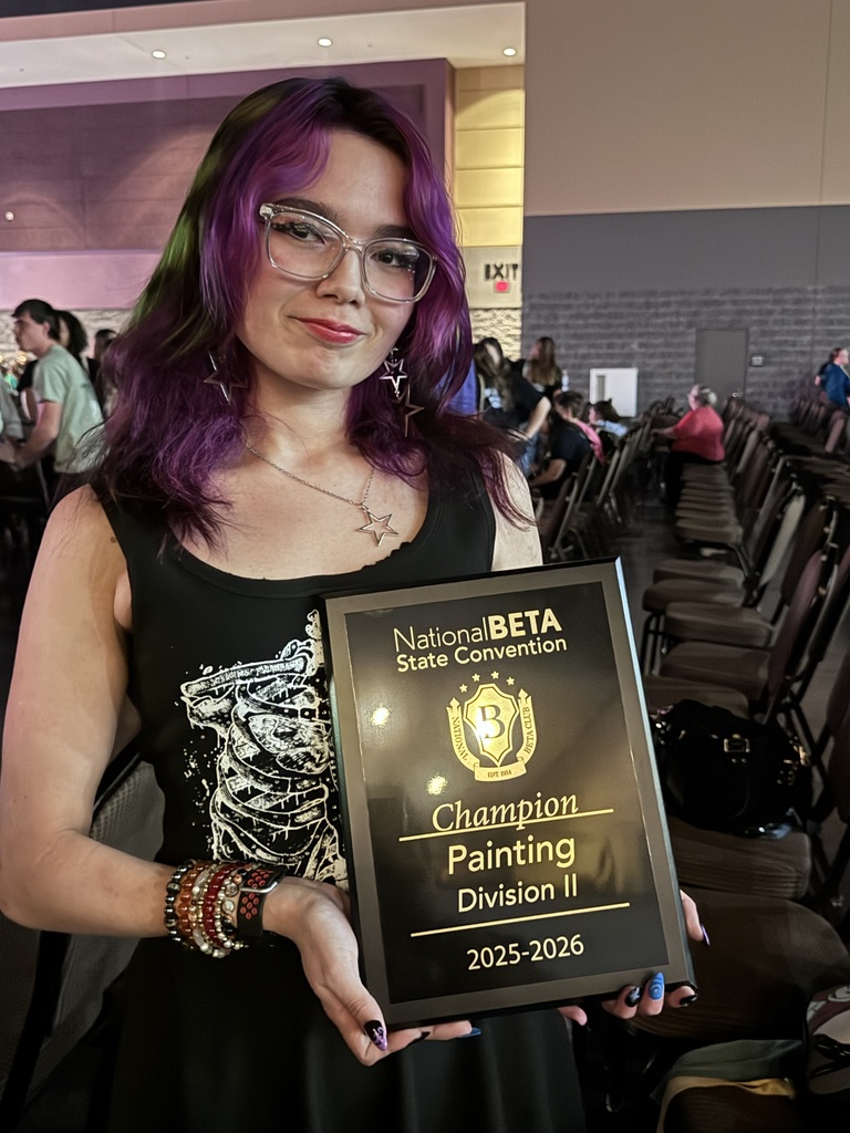 A girl with purple hair and glasses poses with a plaque that reads "Champion Painting Division II 2025-2026."