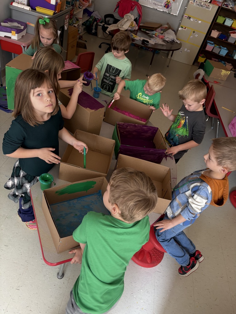Kids in a classroom engaging in an art project. They are using cardboard boxes and paint.