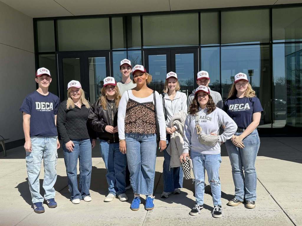 A group of people in matching outfits stand in front of a building with glass walls.