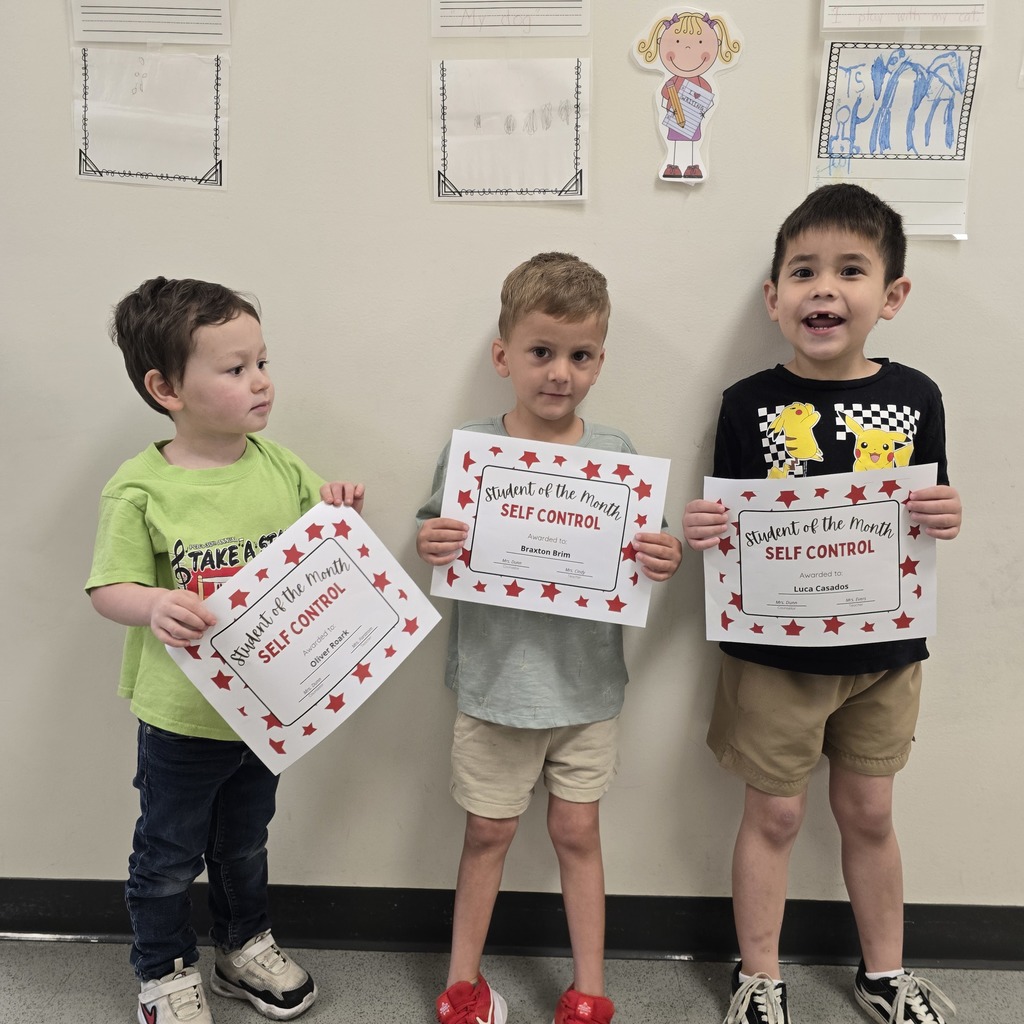 Three young boys stand together, each holding a certificate. They wear casual summer clothes and sneakers.