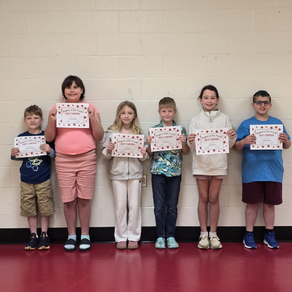 Six children hold certificates and pose for a photo in a room with red flooring.