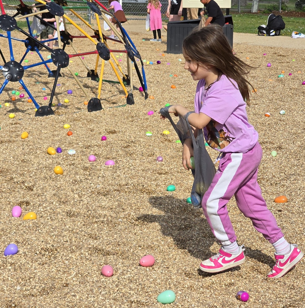 A girl in pink pants and sneakers is walking on a playground with colorful eggs on the ground.