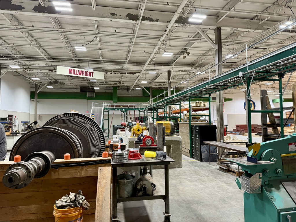 A large industrial factory with metal beams and machines. A red sign is on the wall.