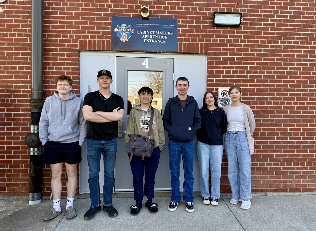 Group of six people standing in front of a brick building with "Carnet Makers" entrance sign.