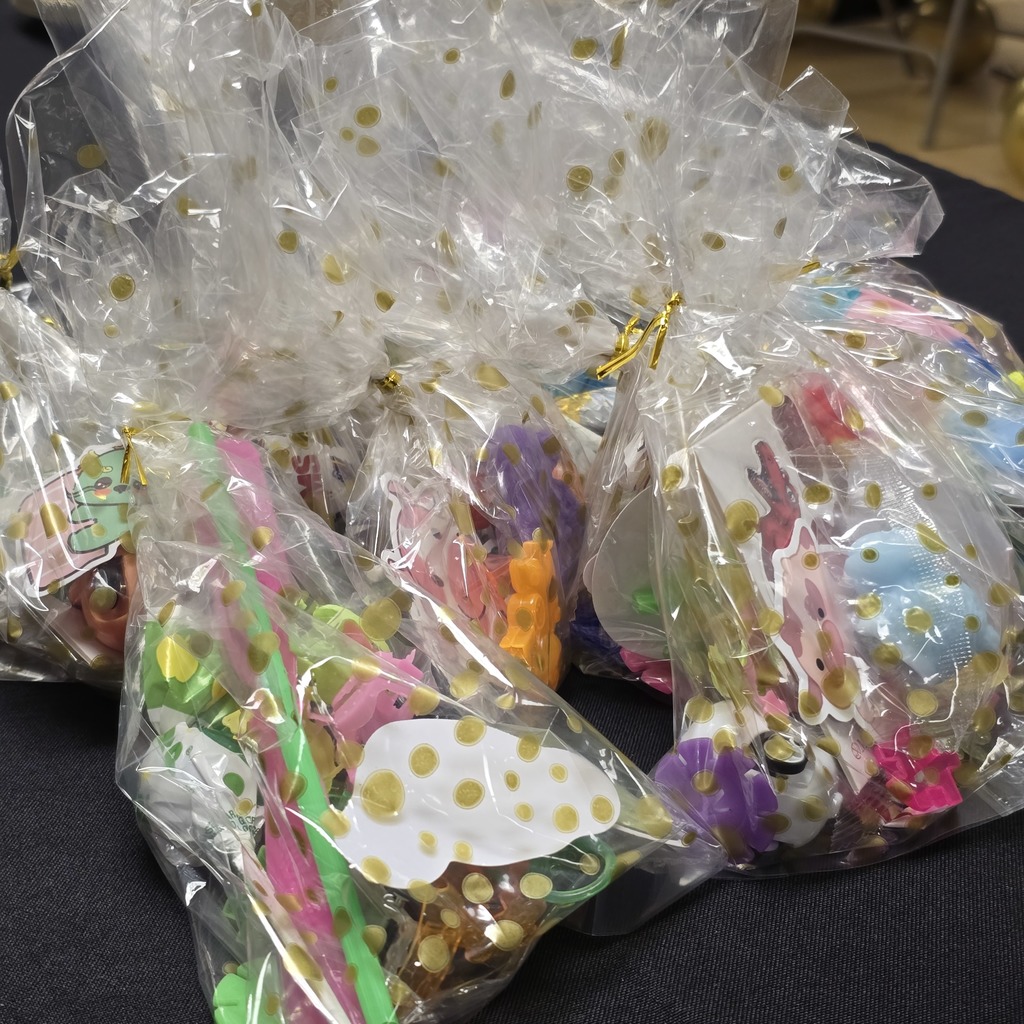 Multiple plastic bags with party favors, including toys and candies, on a table. The bags are tied with ribbon.