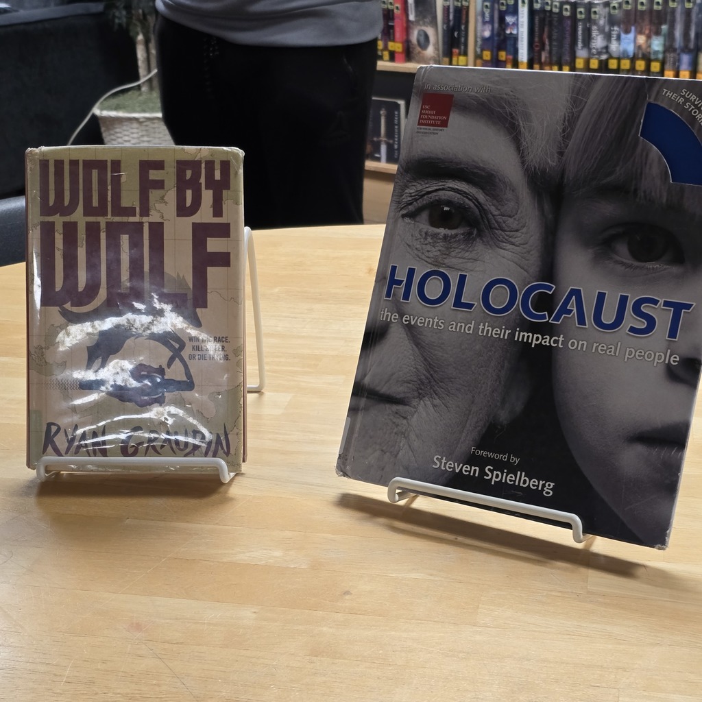 Two books on a table. One is titled "Wolf by Wolf" by Rym Greven. The other is titled "Holocaust" by Steven Spielberg.
