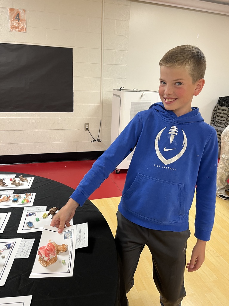 A child in a blue hoodie stands at a table with food samples and educational materials.