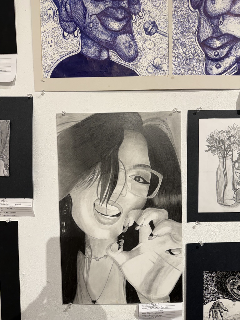 Art pieces on a wall, including a smiling woman in glasses, an abstract face, and a vase.