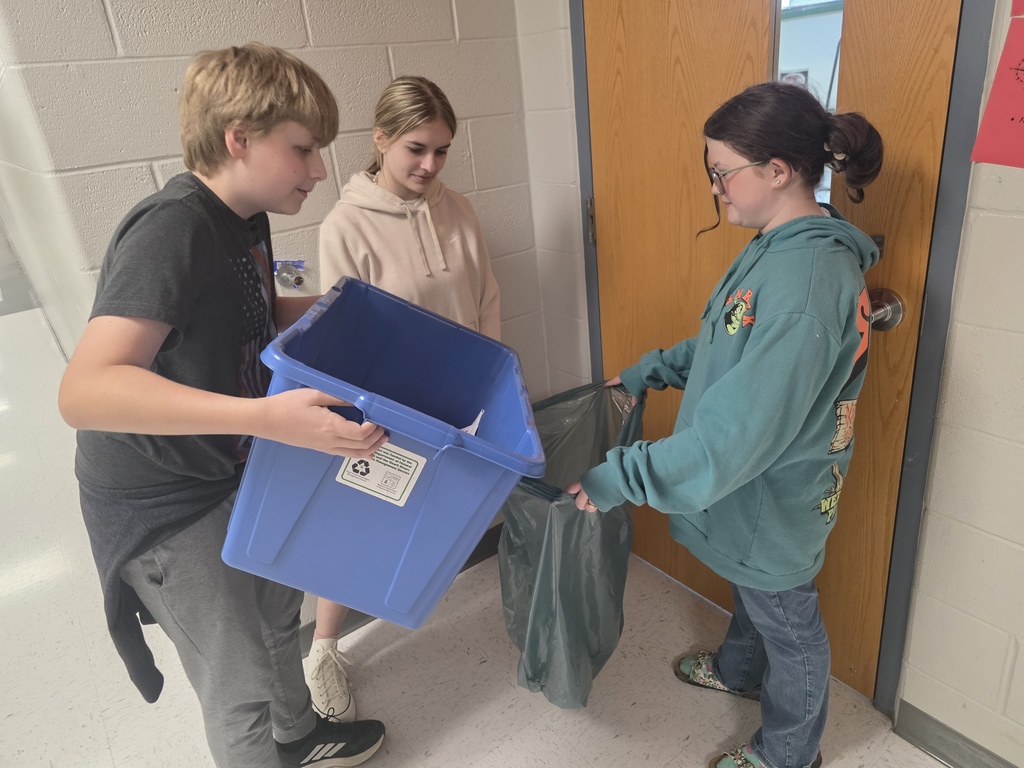 Three individuals, including two youths and an adult, engage in sorting recyclables inside a room.