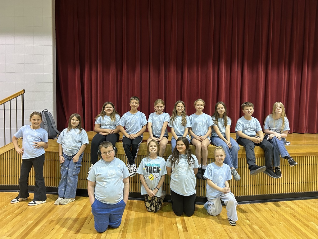 A group of young people in matching shirts pose for a photo on a stage.