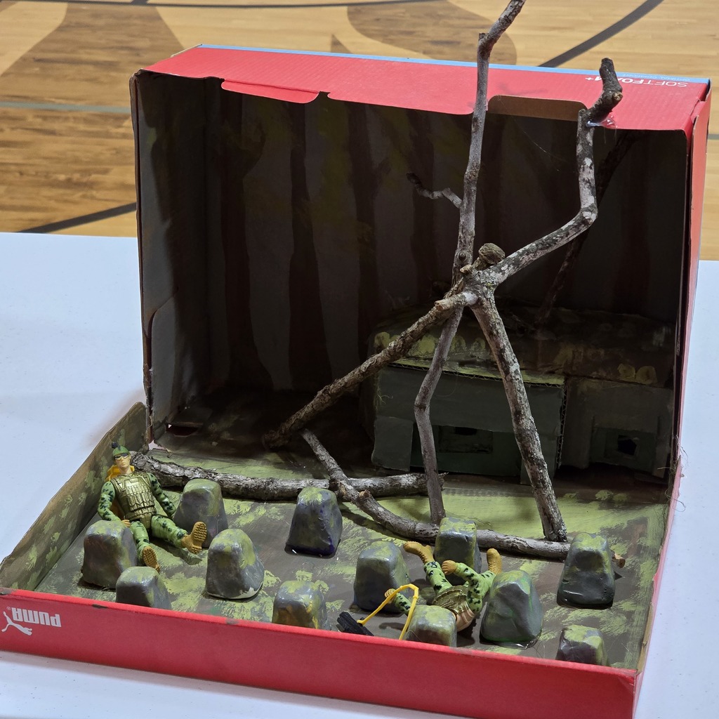 A red box model scene with a tree branch, stones, and green moss. The box is open.