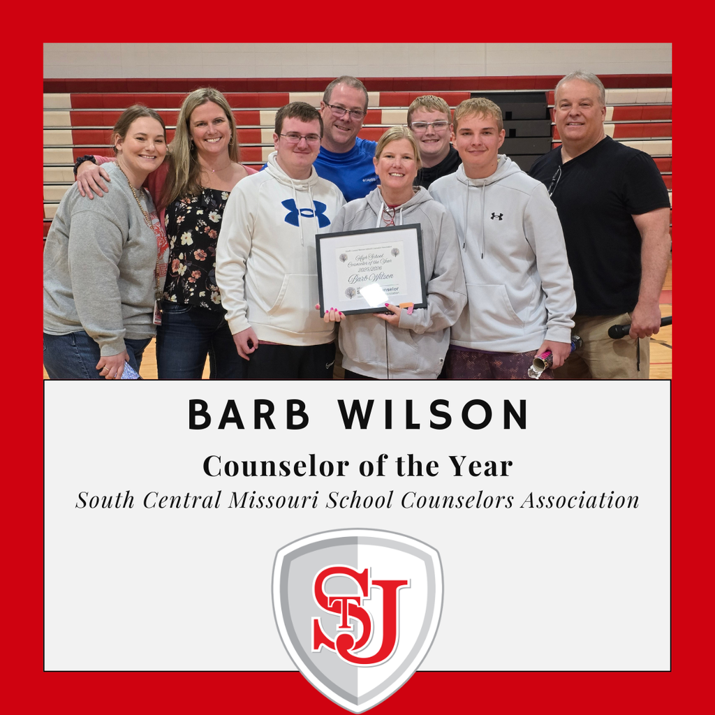 A group of seven people, including a woman holding an award, standing in a gymnasium. "BARB WILSON Counselor of the Year" text is displayed.