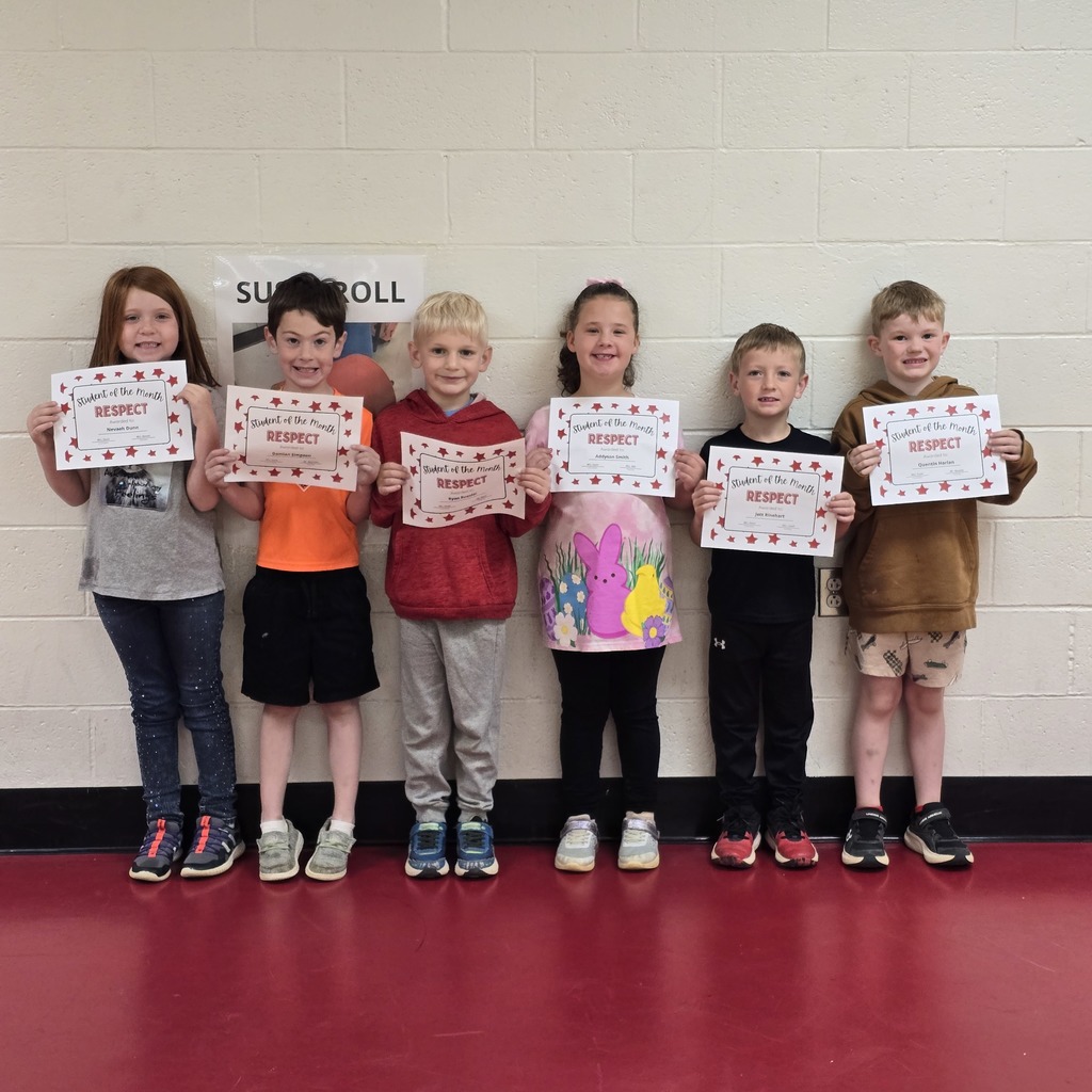 Seven children in a row, holding certificates, standing in front of a white wall with a black border.