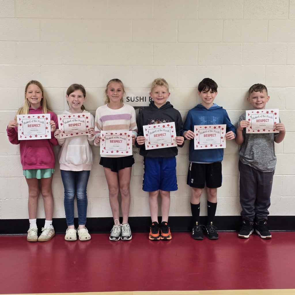Six children standing in a row, holding certificates with text and images. They are in a room with a red floor.