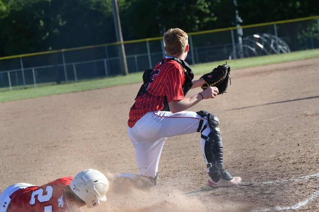 Two players in red and white uniforms, one sliding into base while the other prepares to catch the ball.