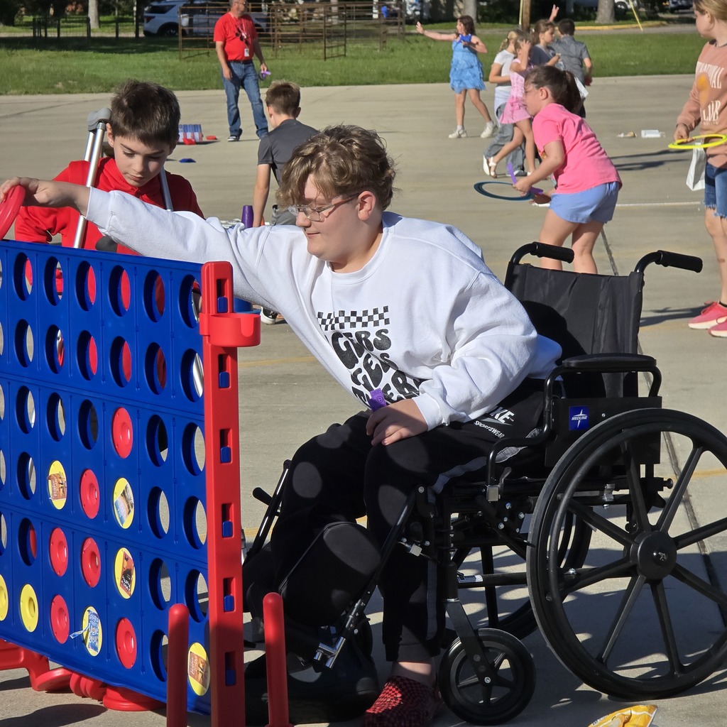 A person in a wheelchair plays a game of Connect Four with another person.