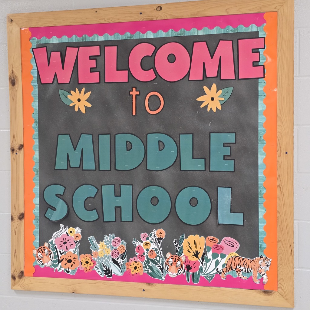 A blackboard with "Welcome to Middle School" written in blue and pink letters. Colorful flowers decorate the bottom.