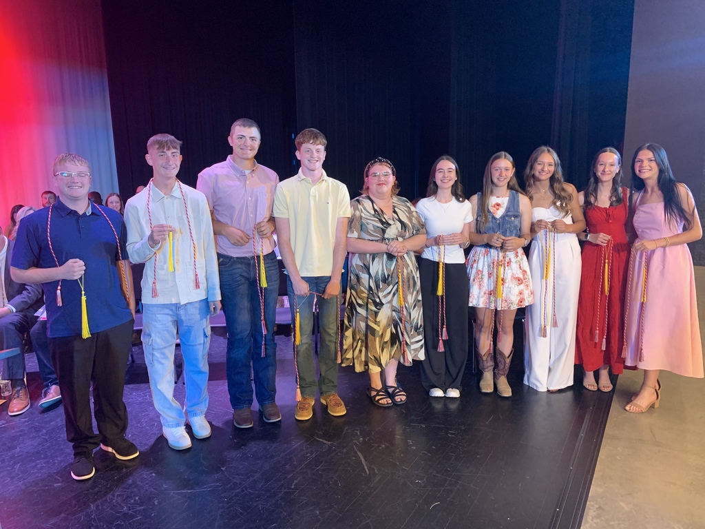 A group of people wearing various colored clothing and shoes standing on a stage, holding certificates.