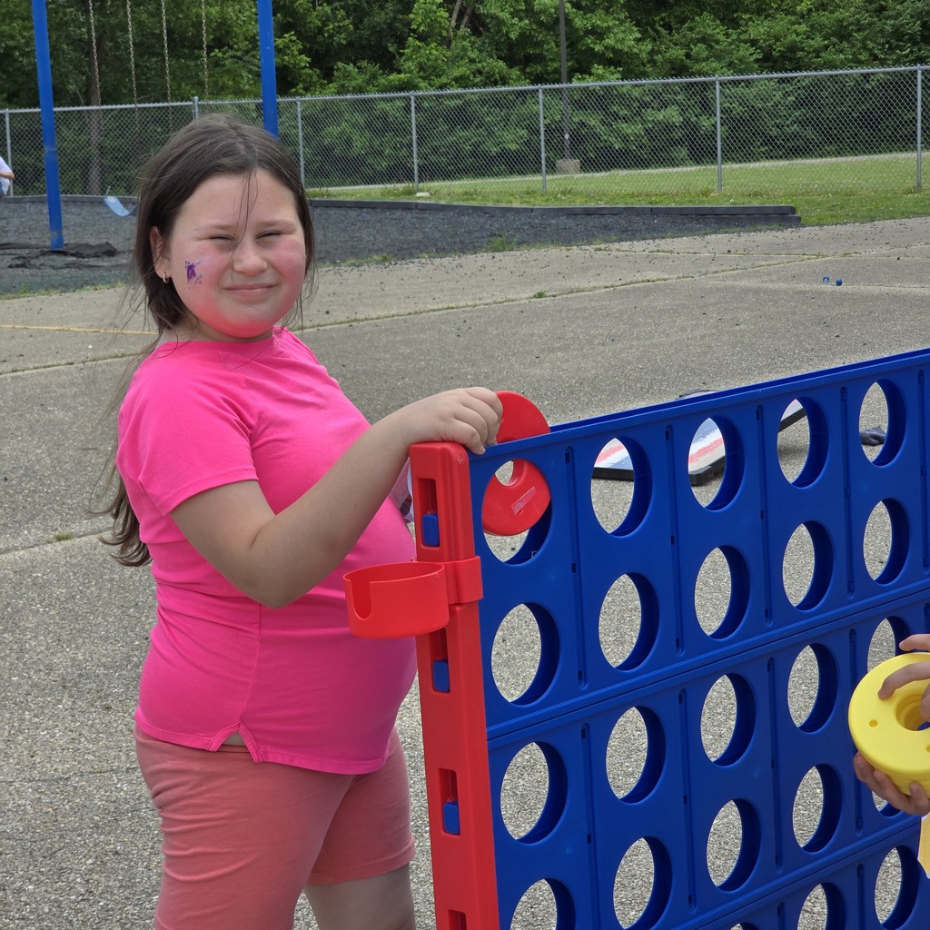 A young person in a pink shirt and shorts plays with a blue and red game board.