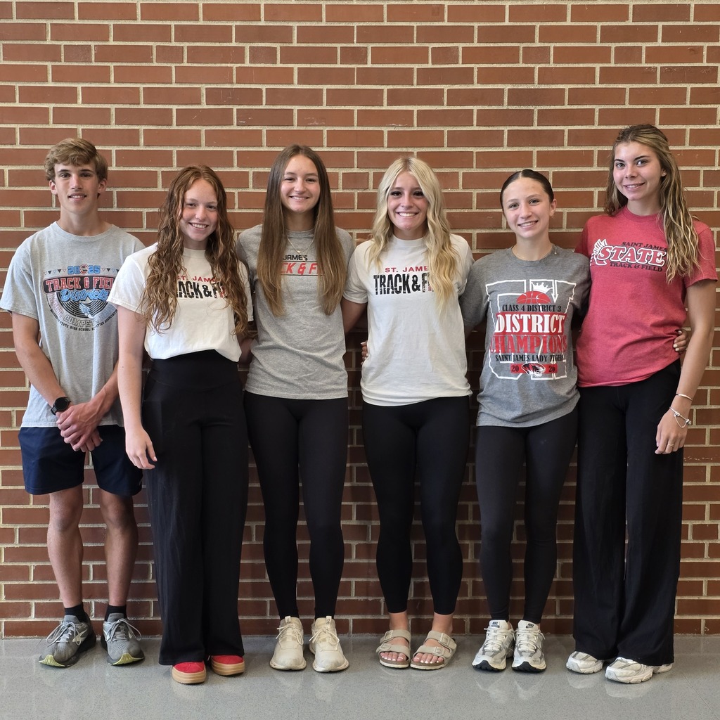 Track students stand against a brick wall.