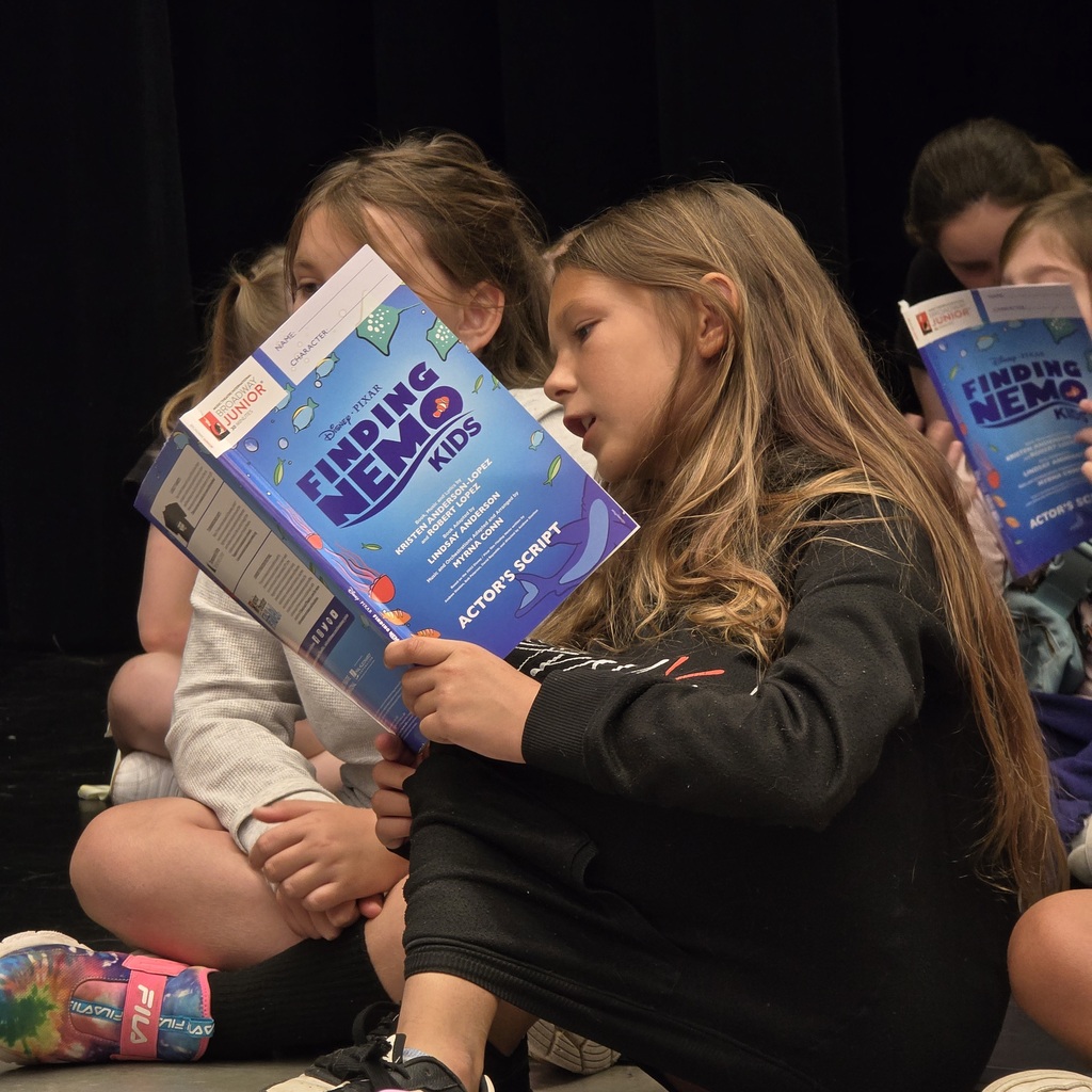 Girls sit on floor reading "Finding Nemo Kids" books. One girl has dark hair, one has light hair.
