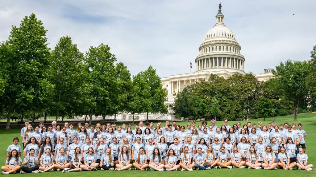A group in matching shirts poses for a photo in front of the Capitol building.