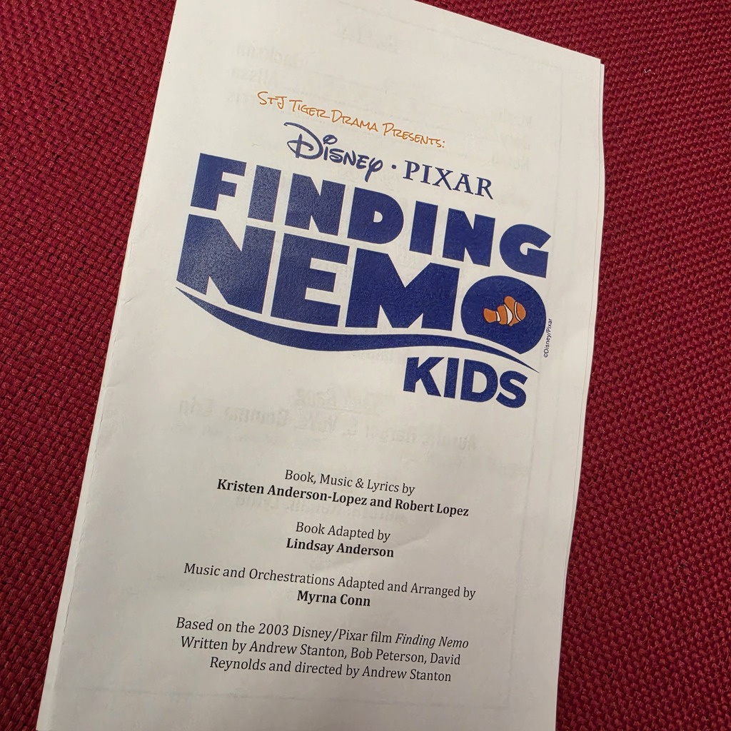 A white program for "Finding Nemo Kids" is on a red background. It features blue text and has a Disney-Pixar logo.