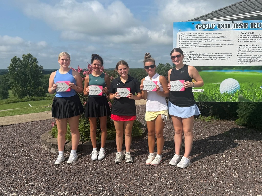 Five women stand in front of a golf course sign, all holding certificates and smiling for a photo.
