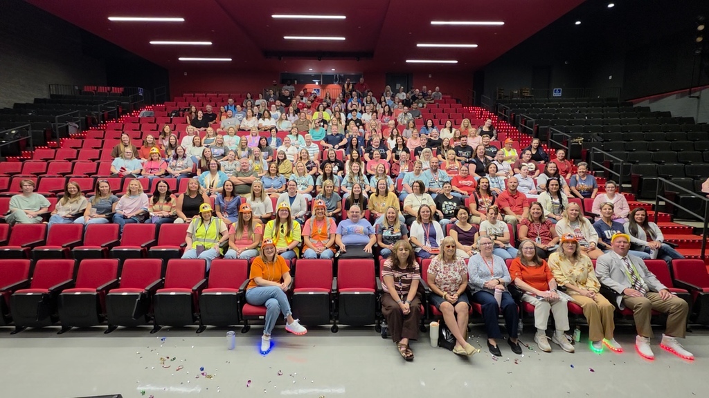 District staff sits in red chairs in the auditorium. 