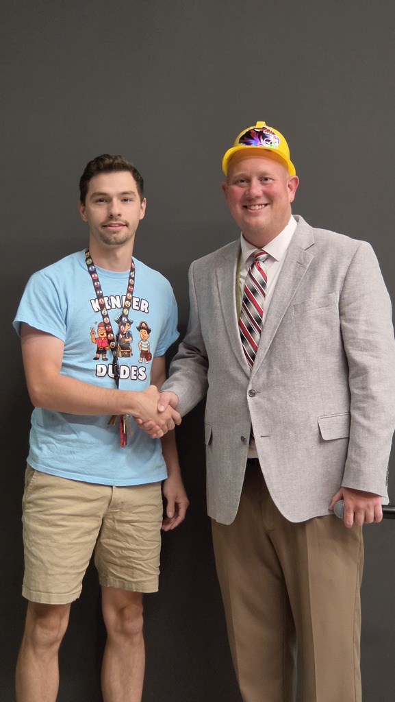 Two men stand shaking hands.