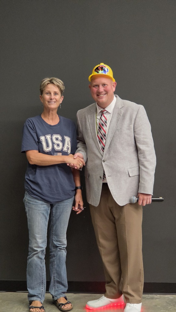 A woman and man stand shaking hands. 
