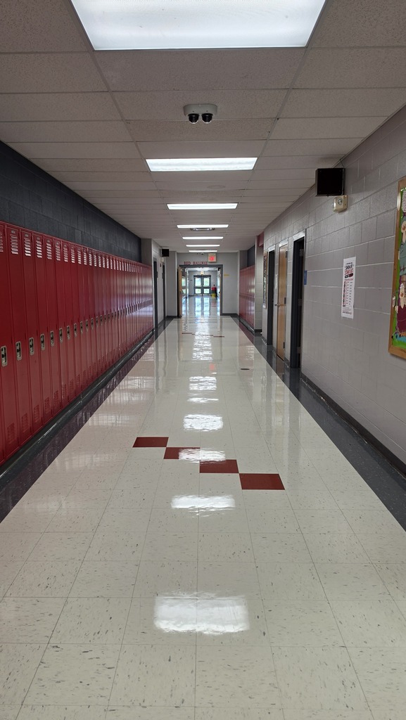 Long hallway with red lockers, white tile floor, black trim, and red checkerboard patterns.