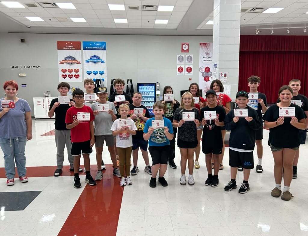 A group of middle school students stand together holding certificates.