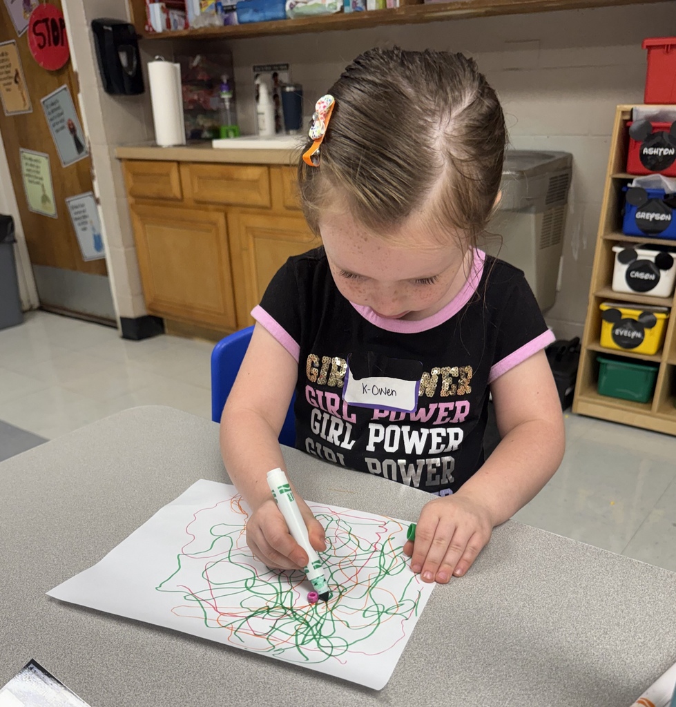 A child draws on a white sheet with green markers.