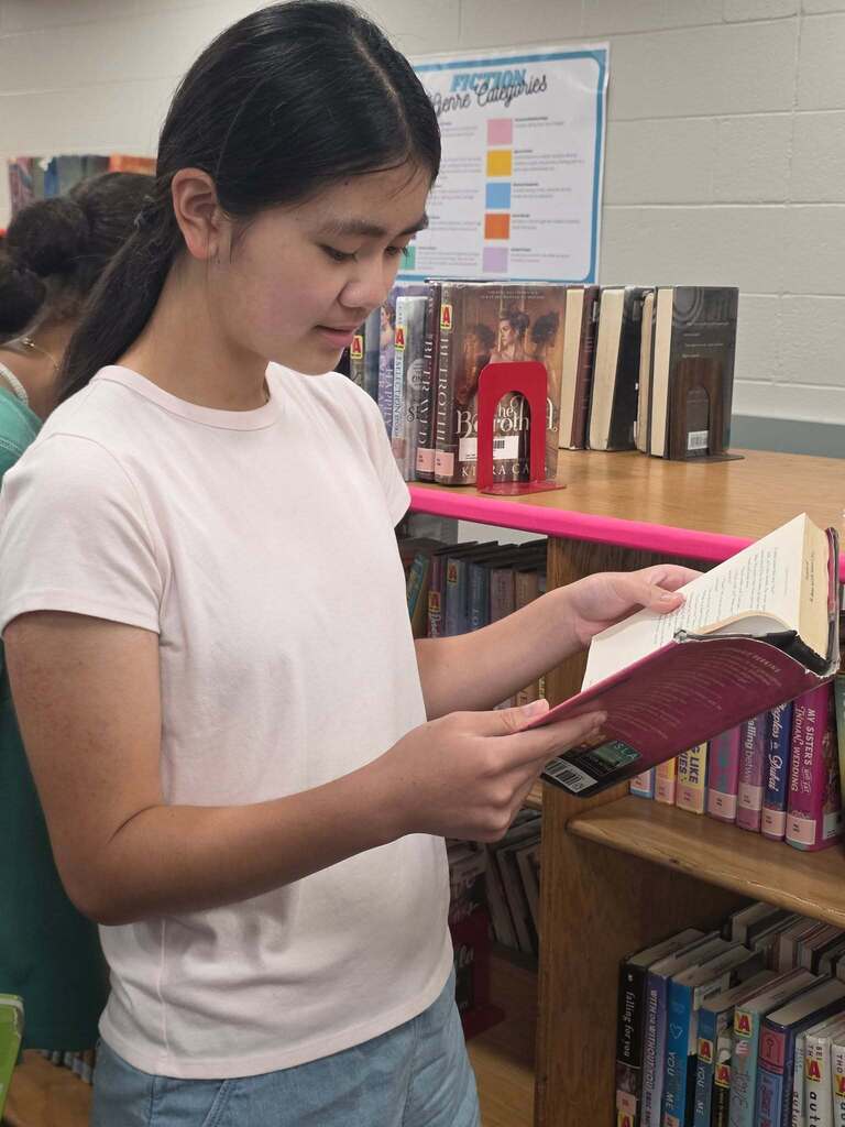 A girl reads a book in a library. 