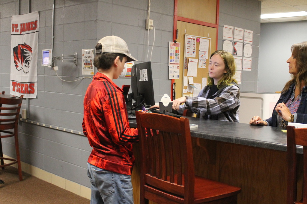 Student checking out book.
