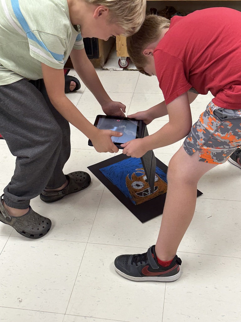 Students take photographs of their artwork to upload into Artsonia, the digital art gallery.