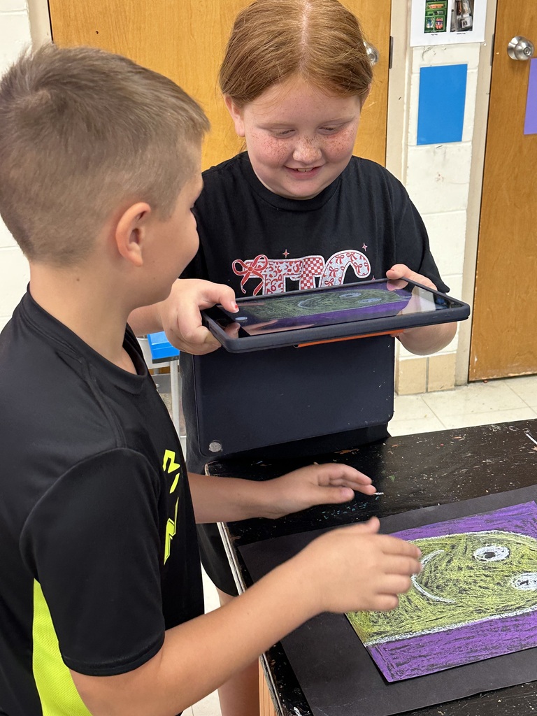 Students take photographs of their artwork to upload into Artsonia, the digital art gallery.