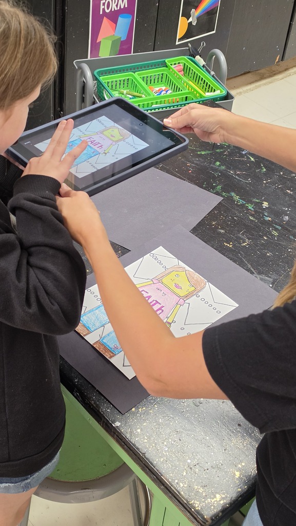 Students take photographs of their artwork to upload into Artsonia, the digital art gallery.
