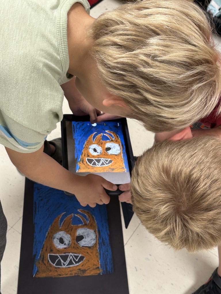 Students take photographs of their artwork to upload into Artsonia, the digital art gallery.