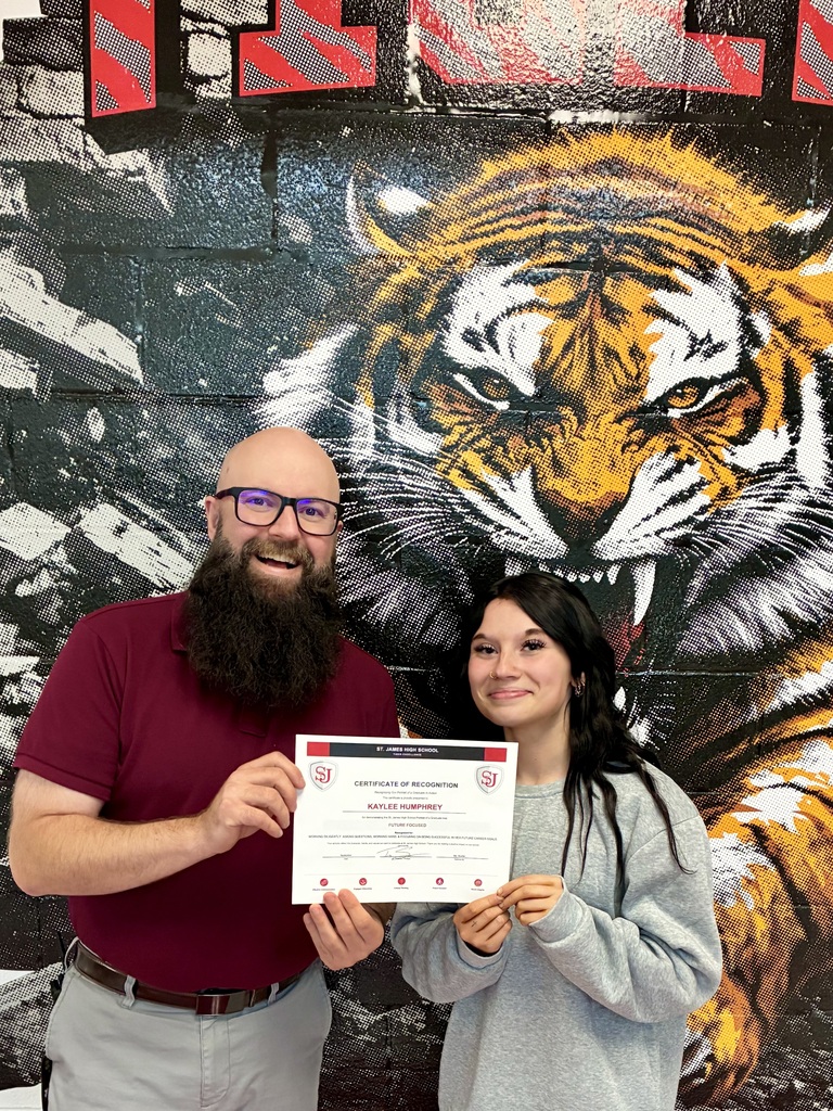 Man and woman hold a certificate, posing in front of a wall with a tiger mural.